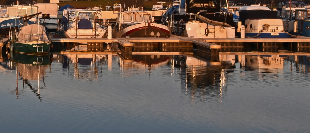 Wohnboote im warmen Licht der Abendsonne, die sich Wasser spiegeln
